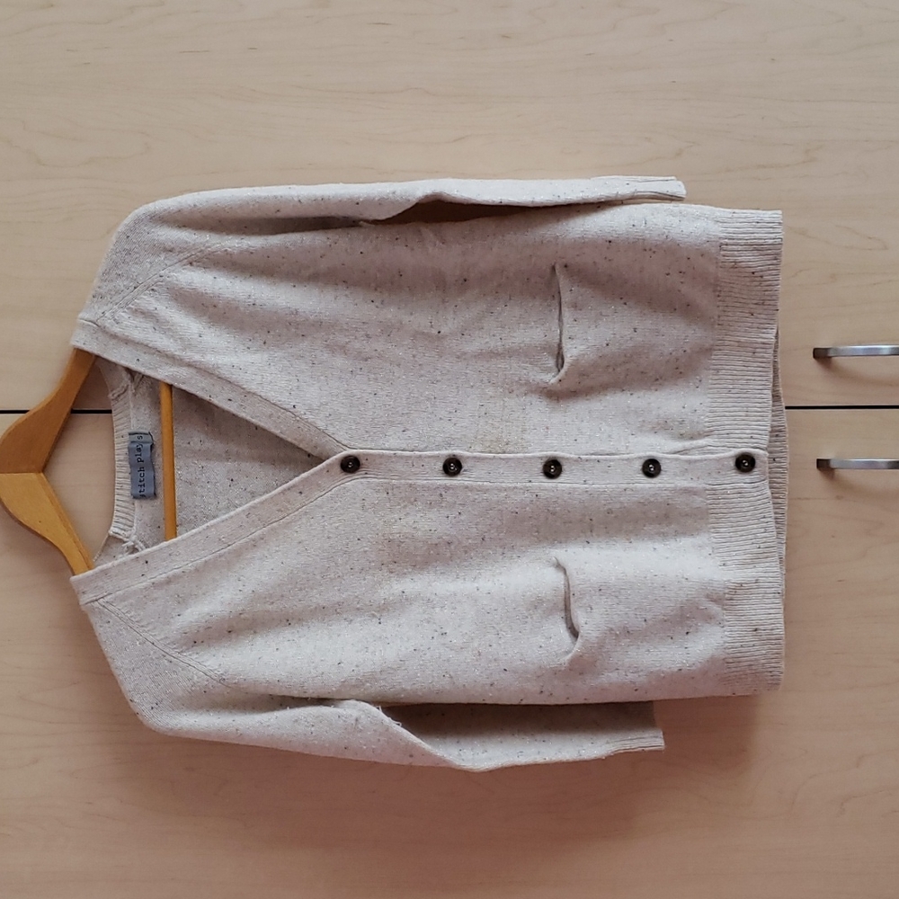 A cream colored long sleeve button-down cardigan with colored dots all around